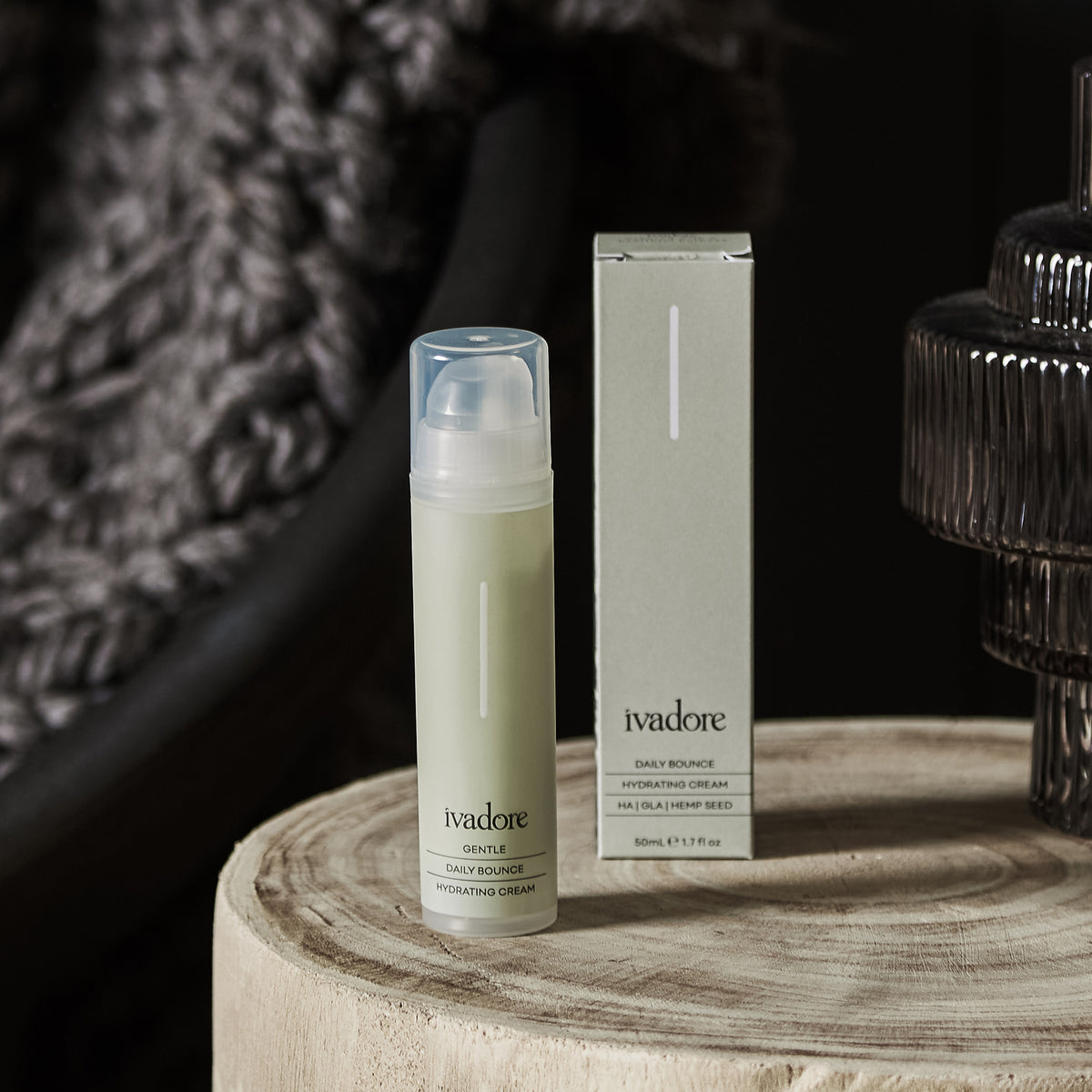 Daily Bounce Hydrating Cream in packaging on wooden table with grey glass vase