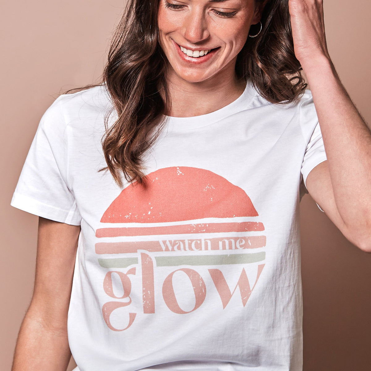 Brown haired girl wearing white tee with slogan &quot;Watch me glow&quot;