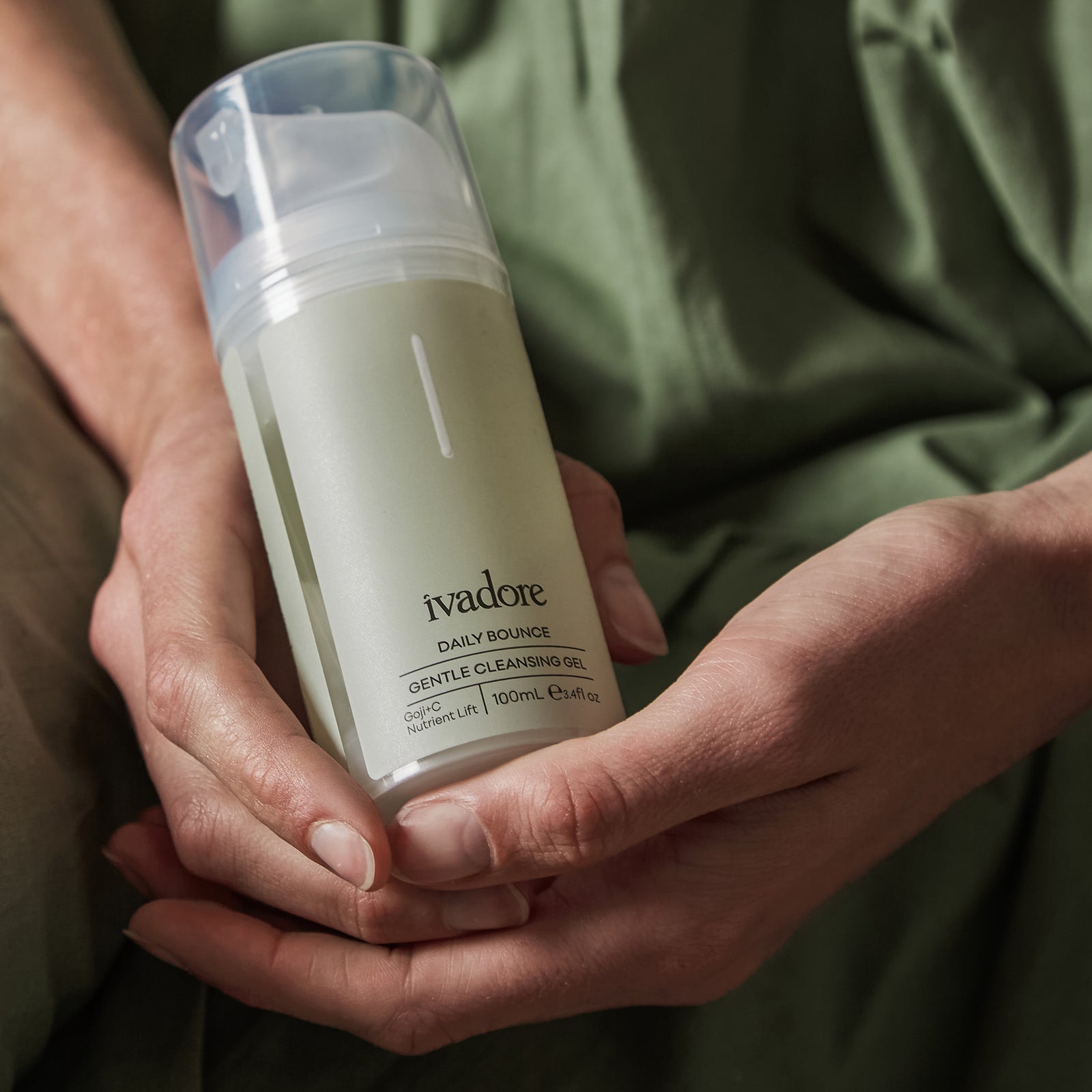 Photograph showing Daily Bounce Cleansing Gel bottle on mint green background with water splashing over it
